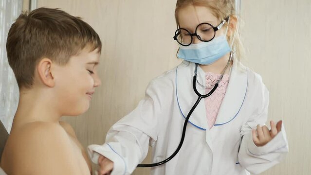 teen brother and sister play in the hospital playing the roles of a doctor and a patient. The girl listens to the boy's breathing with a stethoscope. slow motion