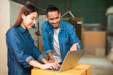 Couple asian entrepreneur work in stock or warehouse industrial, businessman and woman use laptop computer or tablet for check inventory and logistic management.