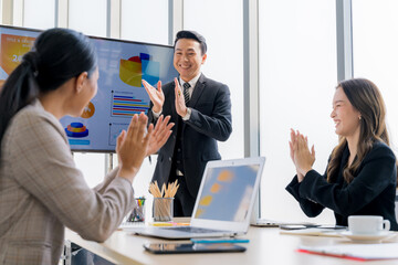 Cheerful young Asian businessman Excited and glad applauded. About successful startup projects Happy Asian colleagues celebrating business success in office meeting.