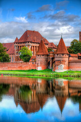 Naklejka na ściany i meble Malbork Castle by the River Nogat, Poland, on a Calm Day