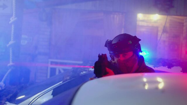 4k Special Force or police man holding weapon near car flasher or roof . Close up view of Police surrounding . Military police or lasertag concept . Shot on ARRI Alexa cinematic camera in slow motion