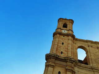 Limestone church during a Maltese sunny blue sky with a bell and clock tower in black and white