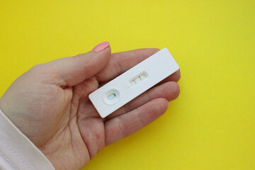 woman is hand holding positive pregnancy test on a yellow background. Motherhood, Pregnancy, Happiness, Children, The Concept of Birth Control. Health problems and problems with conception. Copy space