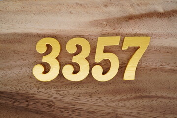 Golden Arabic numerals on a real brown and white wooden floor number 3357