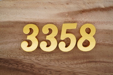 Golden Arabic numerals on a real brown and white wooden floor number 3358