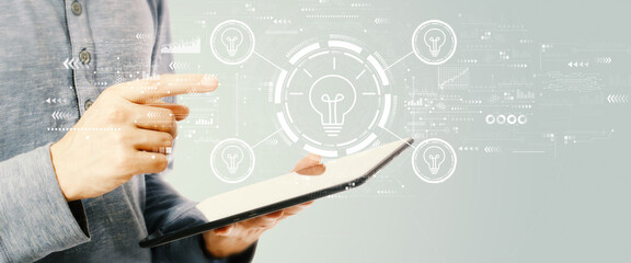 Idea light bulb theme with young man holding a tablet computer
