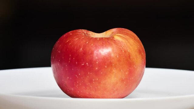 Half apple in plate, rotted from inside, the core is rotten but it looks delicious from outside, 4k footage.