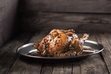 Whole roasted chicken on a plate. Photo of food on a dark background