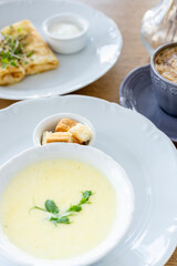Morning breakfast with cheese soup, coffee, croutons, pancakes and greens against the background of backlight.
