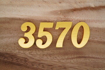 Golden Arabic numerals on a real brown and white wooden floor number 3570