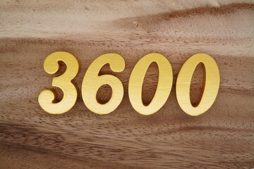 Golden Arabic numerals on a real brown and white wooden floor number 3600