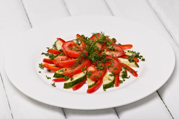 Salad in a plate, tomatoes and cucumbers. Photo of food on a white background