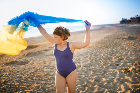 Cute european child teen girl run along the beach by the sea, happy childhood and freedom. Plus size kid, overweight and sports by the sea