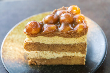 Slice of macadamia cake, coffee layer cake with caramel macadamia nut topping on plate.