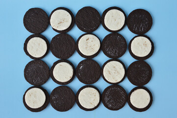 Pattern created by halves chocolate cookies and cream on pastel blue background