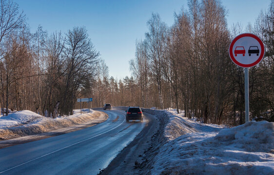 Road sign overtaking is prohibited at the turn of snow-covered highway.