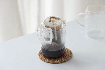 Glass cup with drip coffee bag on white background