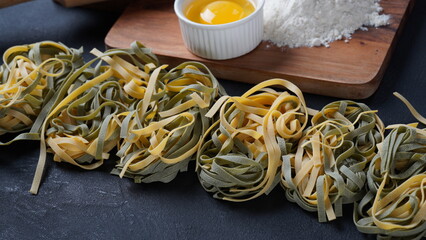 Uncooked Italian homemade egg pasta with spinach placed side by side