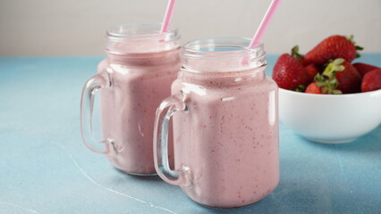 Strawberry milkshake in mason jars with fresh strawberries