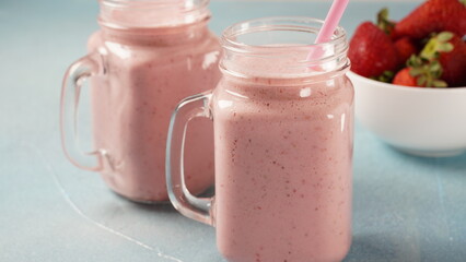 Strawberry milkshake in mason jars with fresh strawberries