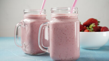 Strawberry milkshake in mason jars with fresh strawberries