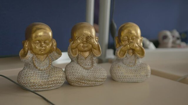 golden figures of three small buddhas on the table in the office at home. three buddha children, one covers his mouth, another covers his ears, the third closes his eyes. buddha symbol. close-up