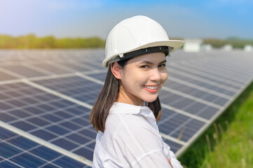 A female engineer wearing helmet in Photovoltaic Cell Farm or Solar Panels Field, eco friendly and clean energy.