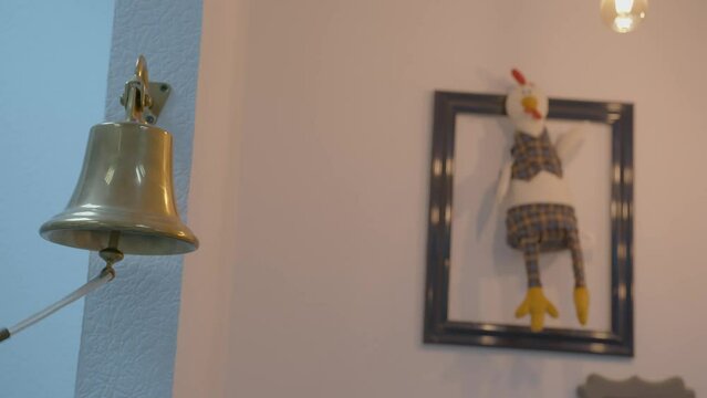a woman's hand pulls the string of a bell for a meeting in the office against the background of the layout of the picture, a toy of a cartoon chicken in a frame. the ringing of a bell in the room