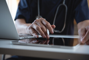 Close up of doctor, surgeon using digital tablet and laptop computer during working in doctor's...