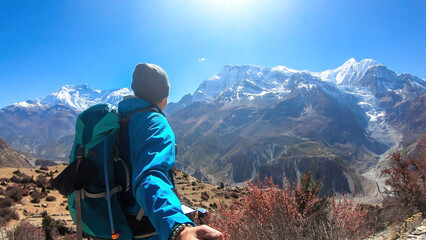 A man hiking and taking a selfie with snow caped Annapurna chain in the back, Annapurna Circuit...