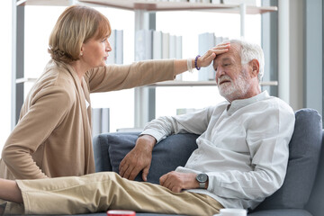 Fototapeta premium senior woman touching forehead her husband on sofa