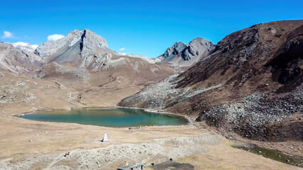 A view on the Ice Lake, along Annapurna Circuit Trek detour, Himalayas, Nepal, surrounded by high mountains. Stupa in front of the lake. Snowy mountain peaks in the back. High altitude lake.