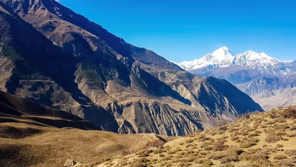 Crédence de cuisine en verre imprimé Dhaulagiri A panoramic view on dry Himalayan landscape. Located in Mustang region, Annapurna Circuit Trek in Nepal. In the back there is snow capped Dhaulagiri I. Barren and steep slopes. Harsh condition.