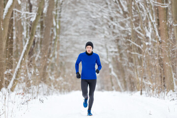 Läufer rennt im Winter durch den verschneiten Park - Ansicht von vorn