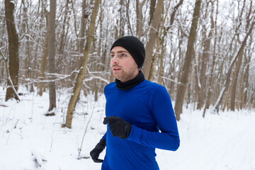 junger jogger bei einer entspannten Laufeinheit durch den verschneiten Wald