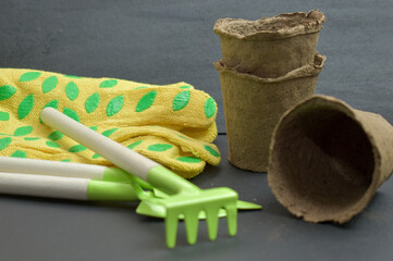 Preparation for gardening. Gardening tools, gloves and peat pots on a black background