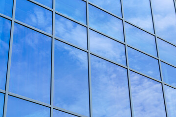 Fototapeta na wymiar glass facade of a modern building, reflection of the blue sky and clouds