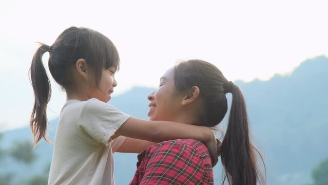 Happy little daughter hugs and kisses her mother in the park. family relationship concept