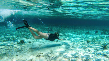 A woman in masker and fins snorkelling in a vivid coral reef in Komodo National Park, Indonesia....