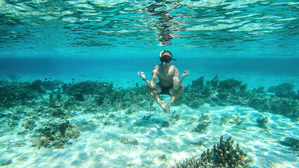 Man in masker and fins snorkelling in a vivid coral reef in Komodo National Park Indonesia. The man...