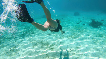 A woman in masker and fins snorkelling in a vivid coral reef in Komodo National Park, Indonesia....
