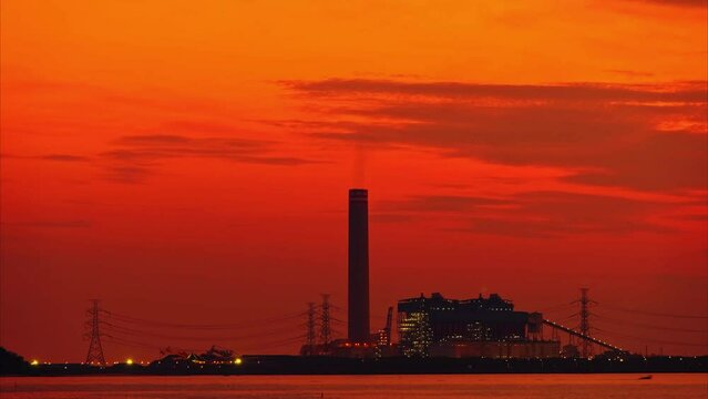 Petrochemical plant or oil and gas refinery industry with flare stacks in silhouette image on orange sky sunset background
