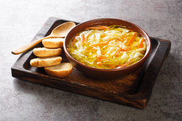 Healthy diet vegetable julienne soup served with toast close-up in a bowl on a wooden tray....