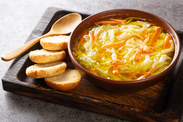 Vegetarian vegetable julienne soup served with toast close-up in a bowl on a wooden tray. Horizontal