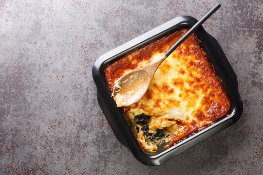 Portuguese casserole Bacalhau espiritual delicious cod cooked with onion, grated carrots sprinkled with grated cheese closeup in the baking dish. Horizontal top view from above
