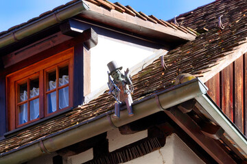 Waving chimney sweep figure with ladder on a house roof