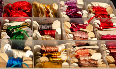 Group of threads of varied colors in small skeins of paper, inside a plastic organizer. Copy space. Technological detox.