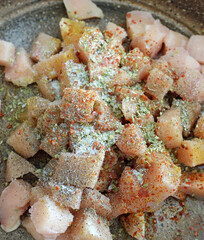 Chicken tenderloin cut into cubes in a pan, topped with pepper, salt, black pepper and dried thyme,