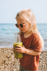 Toddler girl drinking smoothie on beach healthy lifestyle child with glass bottle vegan kiwi beverage organic food summer vacations