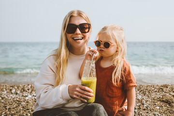Mother and child drinking detox kiwi smoothie summer family vacations on beach healthy lifestyle...